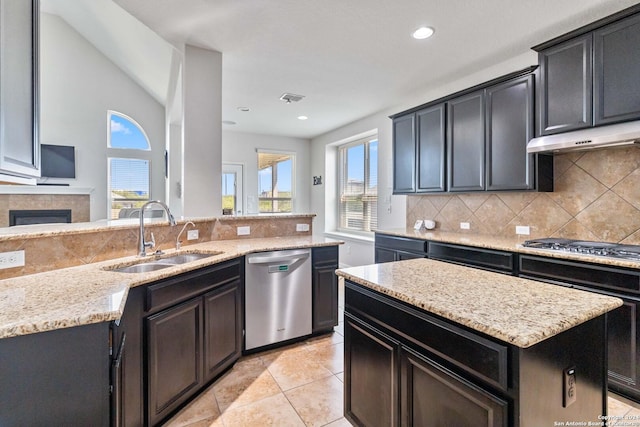 kitchen featuring tasteful backsplash, sink, a center island, stainless steel appliances, and light stone countertops