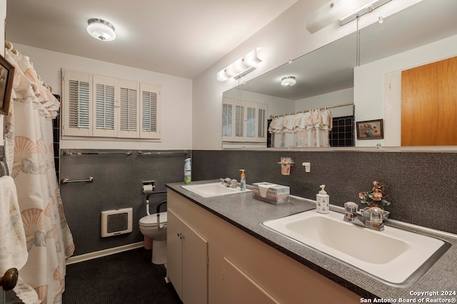 bathroom with dual vanity and toilet