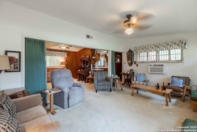 living room featuring light colored carpet, a wall mounted air conditioner, and ceiling fan