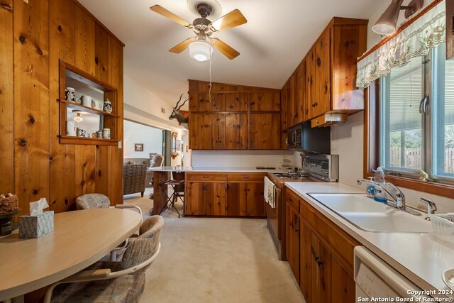 kitchen featuring gas range, sink, ceiling fan, vaulted ceiling, and light colored carpet