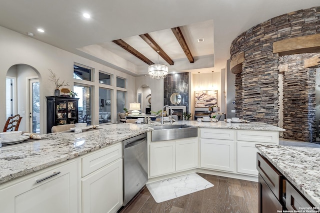 kitchen with pendant lighting, sink, white cabinets, stainless steel dishwasher, and light stone counters