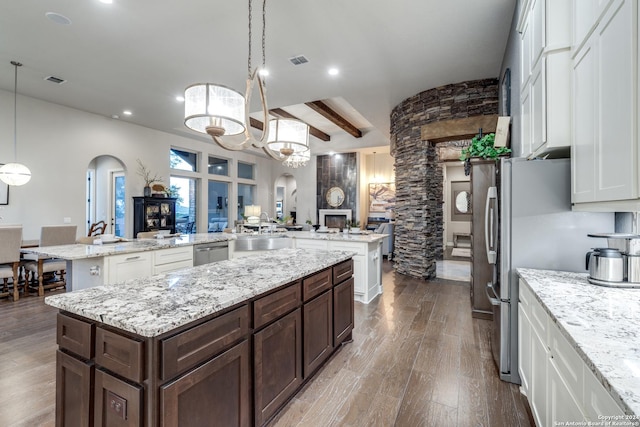 kitchen featuring pendant lighting, dark brown cabinets, a center island, and white cabinets