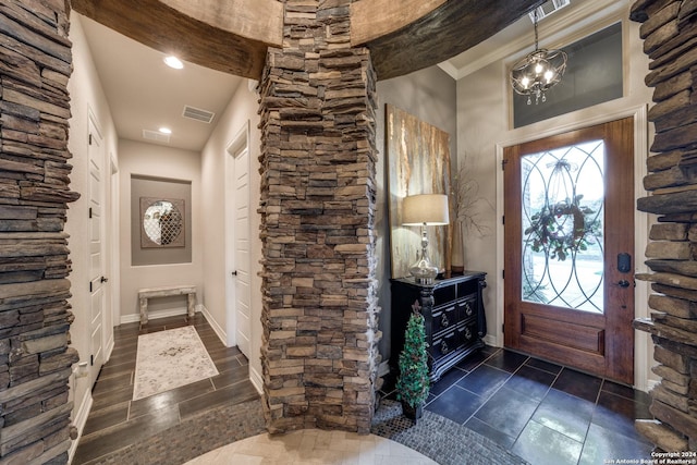 foyer entrance featuring an inviting chandelier and crown molding