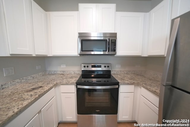 kitchen with white cabinetry, appliances with stainless steel finishes, and light stone counters