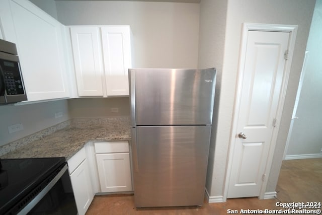 kitchen with stainless steel appliances, white cabinetry, and light stone counters