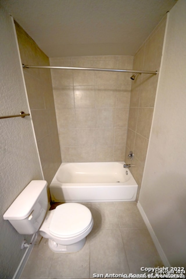 bathroom featuring tiled shower / bath, toilet, and tile patterned flooring