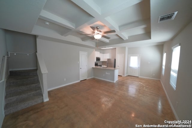 unfurnished living room with coffered ceiling, ceiling fan, concrete flooring, and beamed ceiling