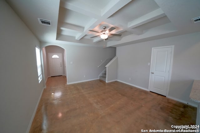 unfurnished living room with coffered ceiling, ceiling fan, concrete floors, and beamed ceiling