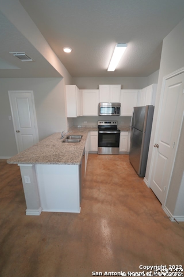 kitchen with sink, white cabinets, kitchen peninsula, stainless steel appliances, and light stone countertops