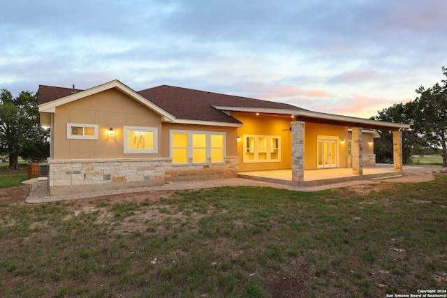 back house at dusk featuring a patio and a yard