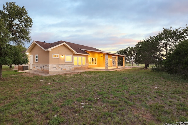 back house at dusk featuring a patio area and a yard