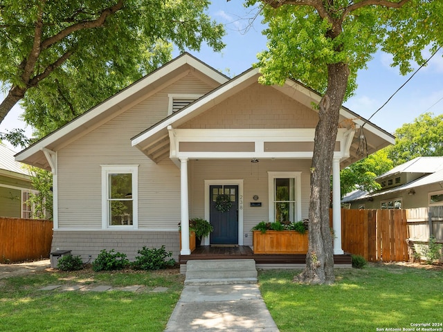 bungalow-style home featuring covered porch and a front lawn