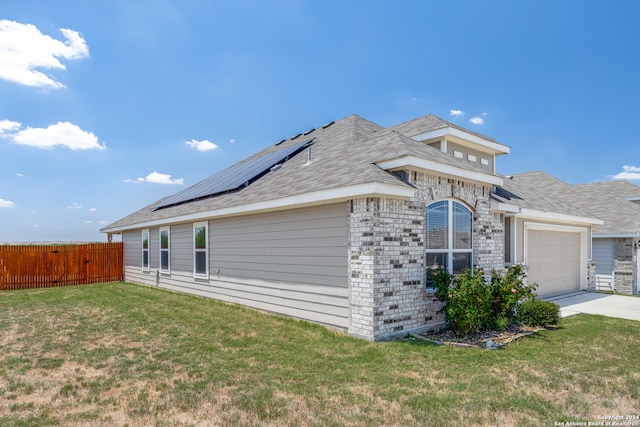 view of side of home featuring solar panels, a yard, and a garage