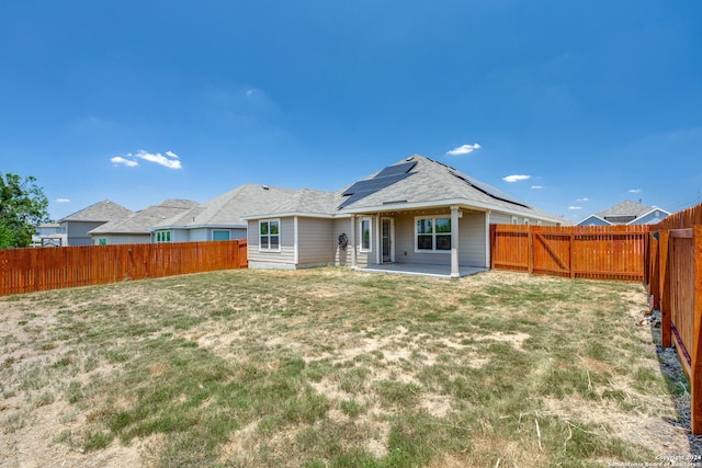 back of property featuring a lawn, a patio area, and solar panels