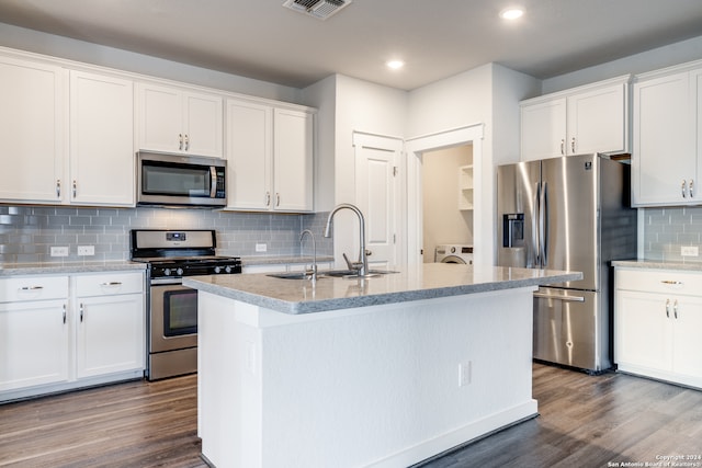 kitchen featuring wood-type flooring, appliances with stainless steel finishes, an island with sink, and backsplash