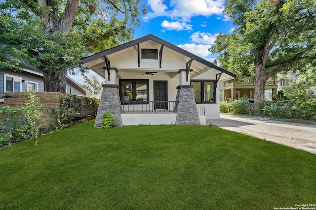 view of front of home with ceiling fan, a front yard, and covered porch