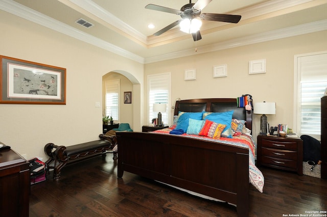 bedroom with dark wood-style floors, visible vents, arched walkways, and crown molding