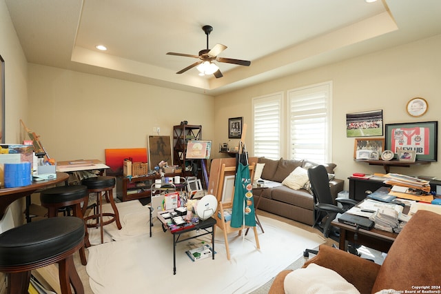 living room with ceiling fan and a raised ceiling