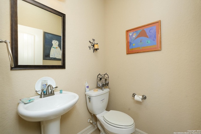 half bath with a sink, toilet, and baseboards