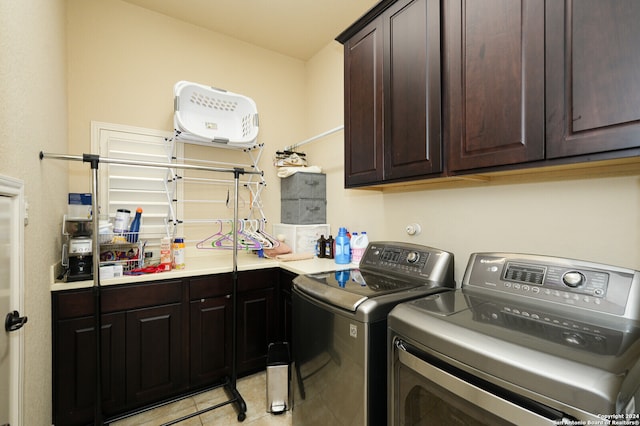 clothes washing area with washing machine and clothes dryer, light tile patterned floors, and cabinets