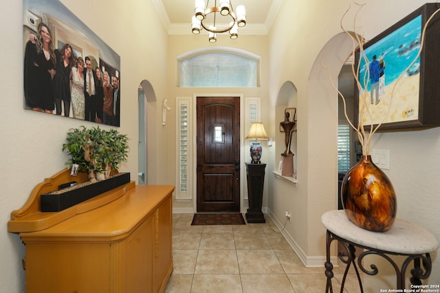 entrance foyer featuring light tile patterned flooring, ornamental molding, and a chandelier