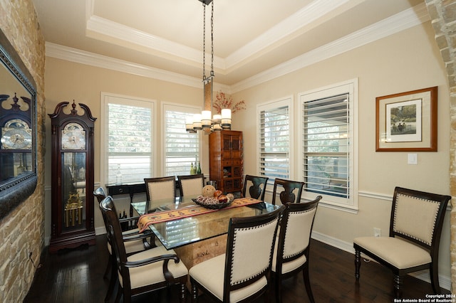 dining space with a tray ceiling, dark wood-type flooring, an inviting chandelier, and crown molding