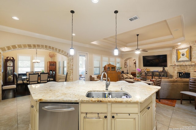 kitchen featuring a center island with sink, arched walkways, light stone counters, open floor plan, and a sink