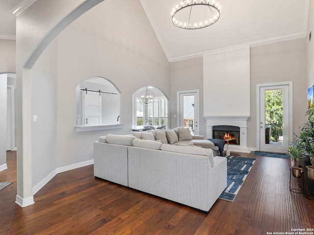 living room featuring high vaulted ceiling, ornamental molding, dark wood-type flooring, and a barn door