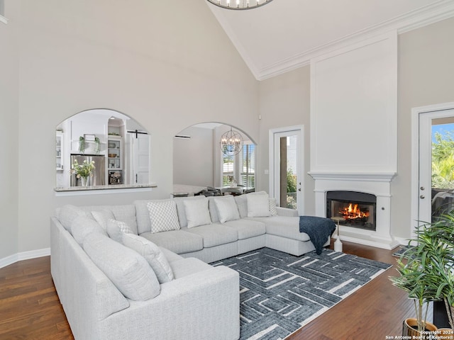 living room with crown molding, an inviting chandelier, dark hardwood / wood-style floors, and high vaulted ceiling