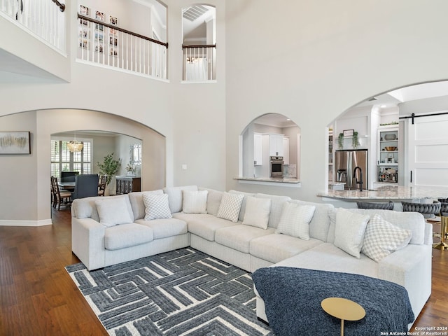 living room with a towering ceiling, a barn door, and dark hardwood / wood-style floors