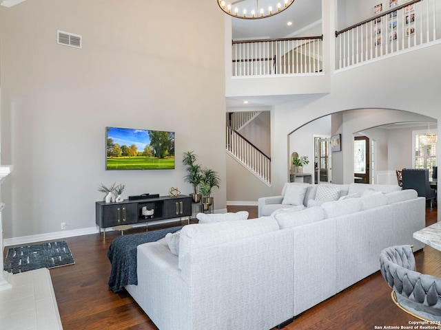 living room with a chandelier, a high ceiling, and dark hardwood / wood-style flooring