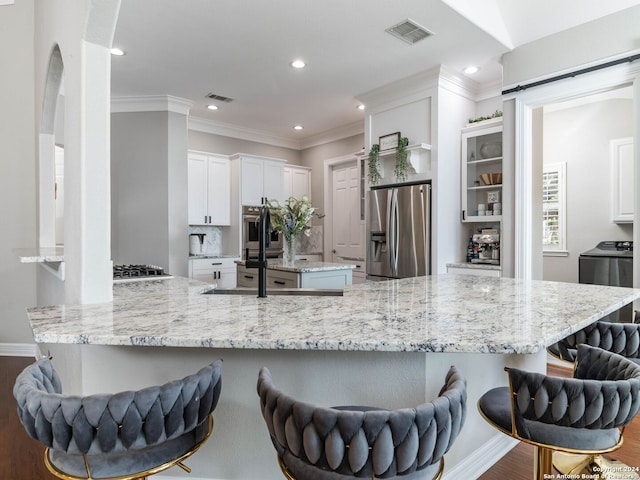 kitchen with a kitchen breakfast bar, stainless steel appliances, white cabinets, and kitchen peninsula