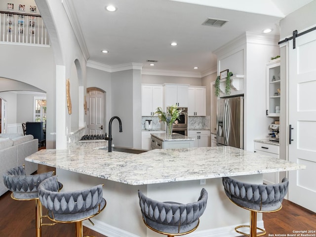 kitchen with sink, white cabinetry, appliances with stainless steel finishes, a breakfast bar area, and a barn door