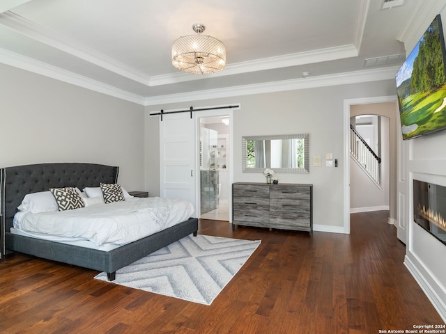 bedroom featuring a raised ceiling, an inviting chandelier, crown molding, a barn door, and dark hardwood / wood-style flooring