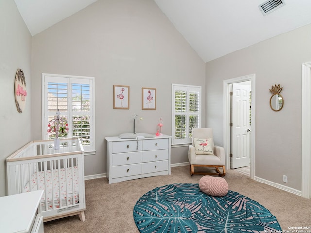 bedroom featuring high vaulted ceiling, multiple windows, a crib, and light carpet