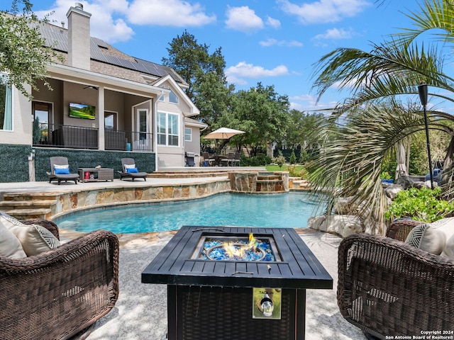 view of swimming pool with a patio area, pool water feature, and a fire pit