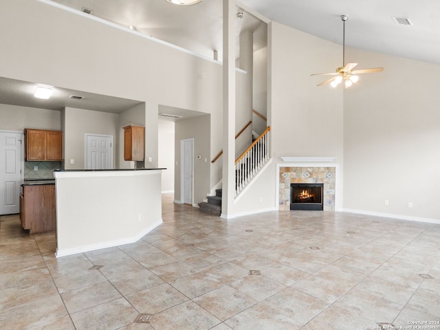 unfurnished living room featuring a tiled fireplace, light tile patterned floors, lofted ceiling, and ceiling fan