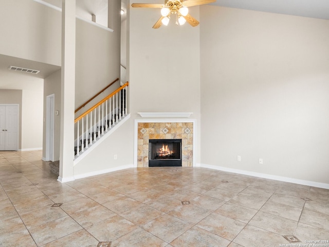 unfurnished living room with a high ceiling, a tile fireplace, light tile patterned floors, and ceiling fan