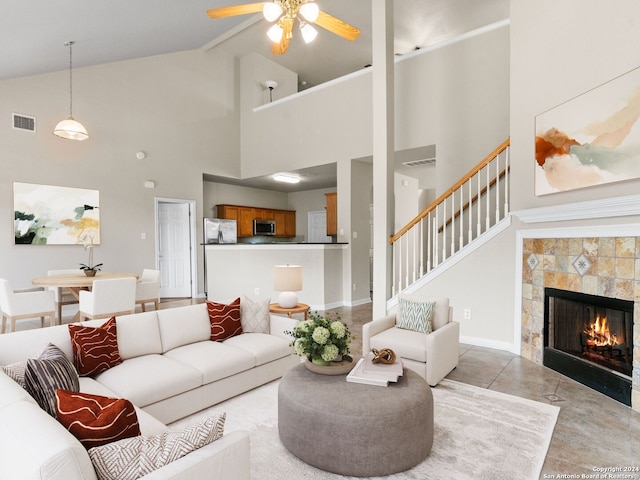 living room with light tile patterned floors, vaulted ceiling with beams, a tile fireplace, and ceiling fan