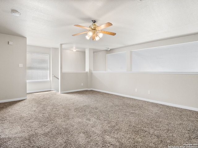 carpeted spare room featuring ceiling fan and a textured ceiling