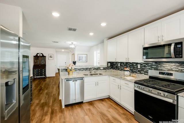 kitchen with sink, light stone counters, appliances with stainless steel finishes, white cabinets, and light wood-type flooring