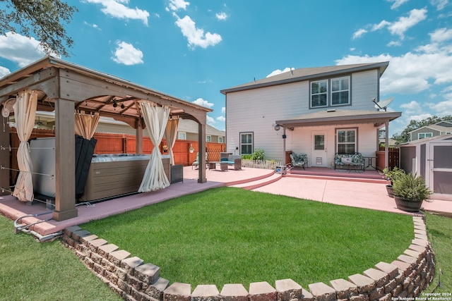 rear view of property with a storage shed, a gazebo, a yard, a patio, and a hot tub