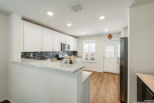 kitchen featuring kitchen peninsula, white cabinetry, light stone countertops, and appliances with stainless steel finishes