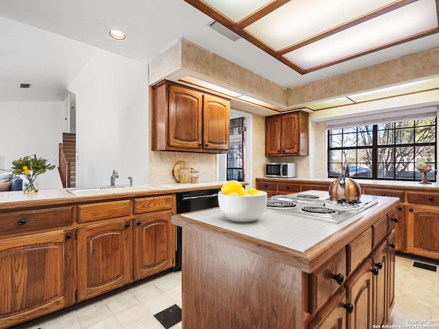 kitchen featuring stovetop, sink, tile countertops, and a center island