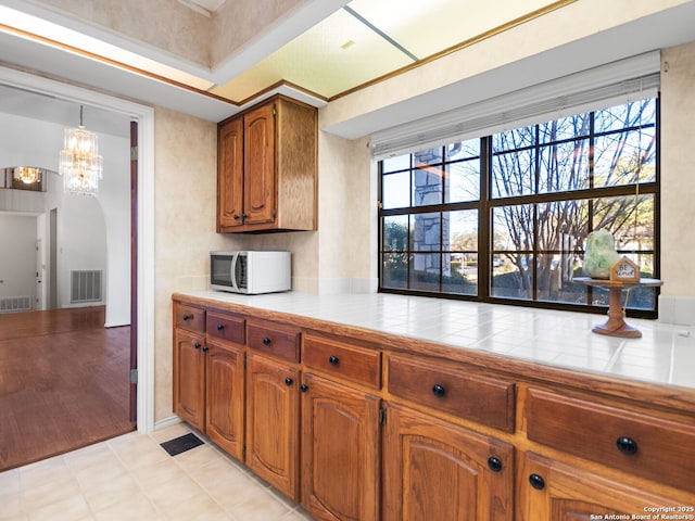 kitchen with hanging light fixtures, tile counters, and a notable chandelier