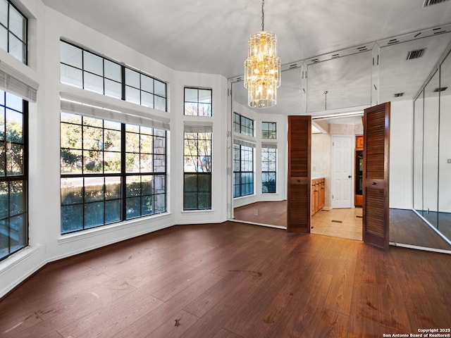 unfurnished living room with an inviting chandelier and hardwood / wood-style flooring