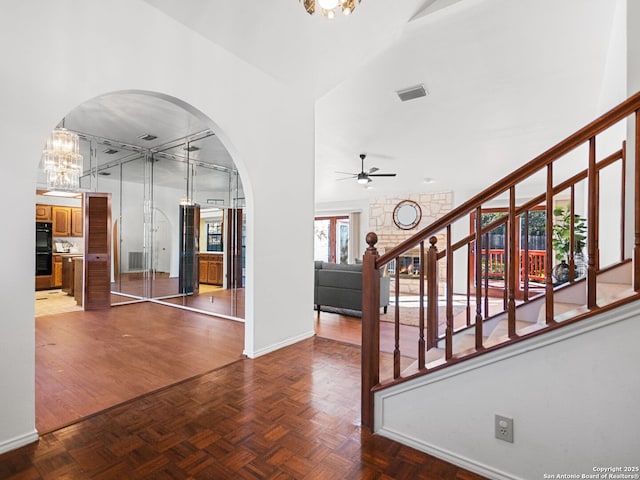 entryway featuring ceiling fan with notable chandelier and parquet flooring