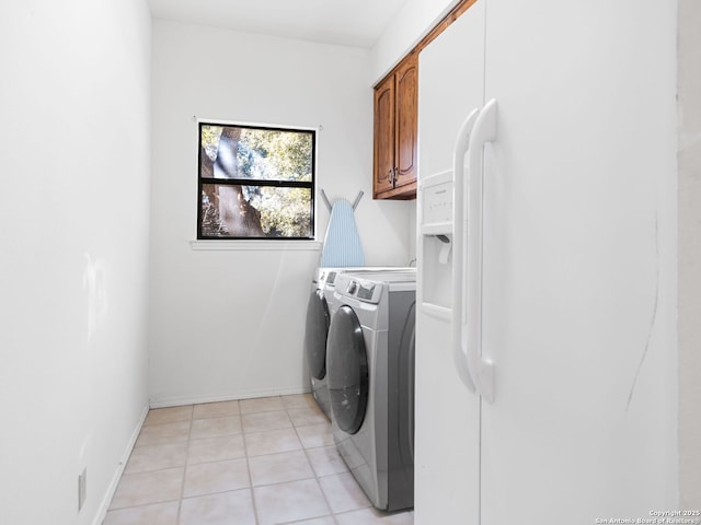 washroom featuring cabinets, light tile patterned floors, and washer and clothes dryer