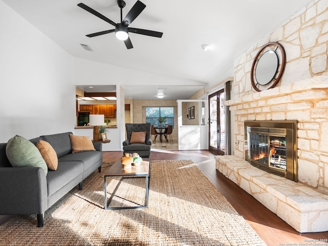 living room with ceiling fan, wood-type flooring, a fireplace, and vaulted ceiling