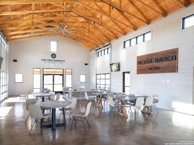 dining space with high vaulted ceiling, concrete floors, and wooden ceiling